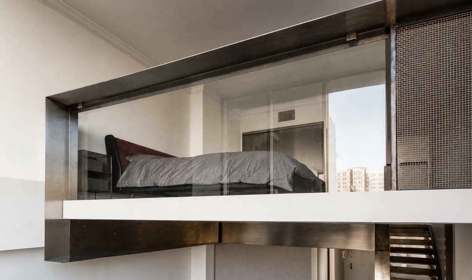  Glass-walled mezzanine bedroom wrapped in a blackened steel frame in an Upper West Side duplex, overlooking a Manhattan rooftop view