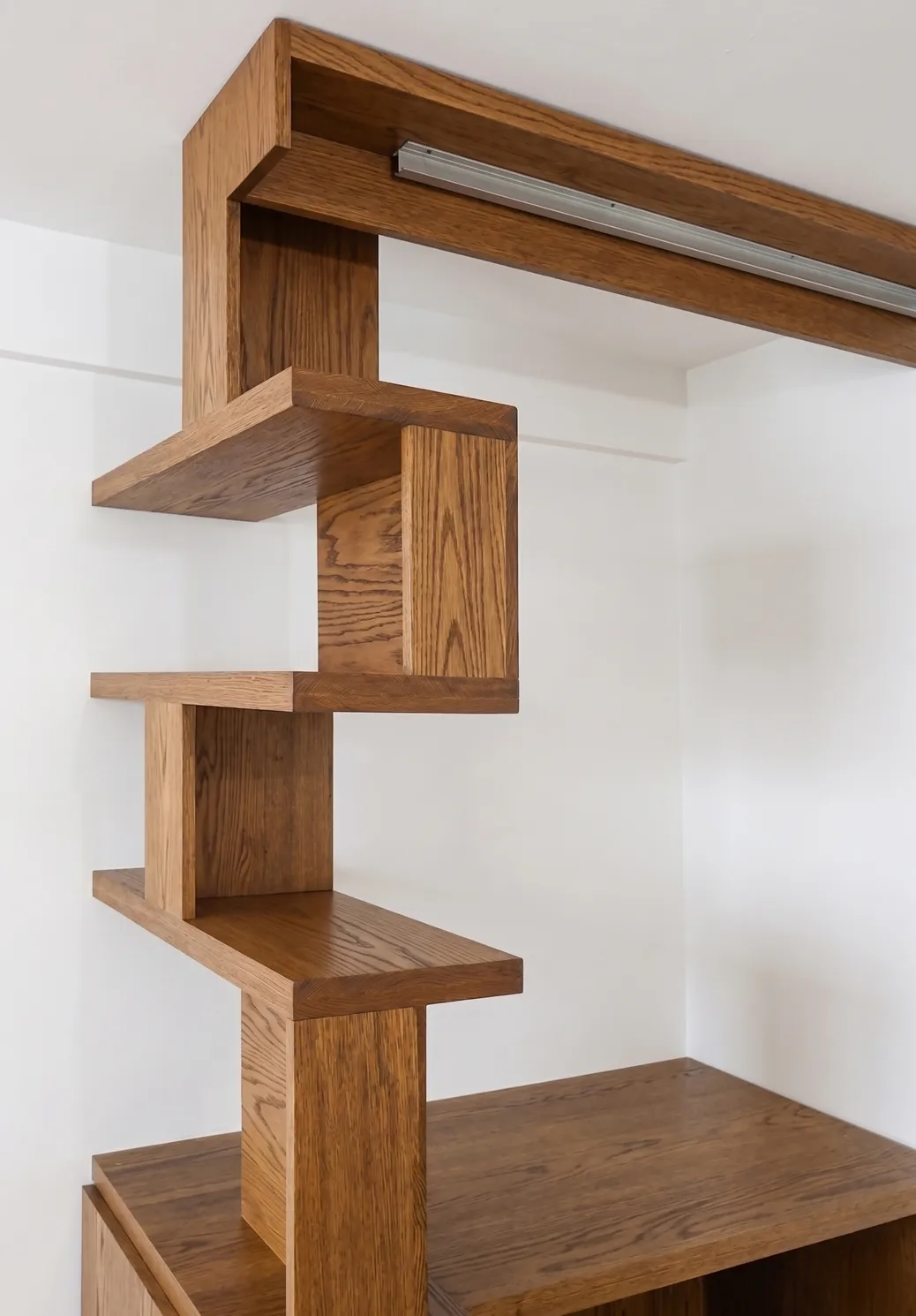 Detail of custom stepped oak shelving built from stock components in a historic Manhattan apartment, with a sliding-panel track above