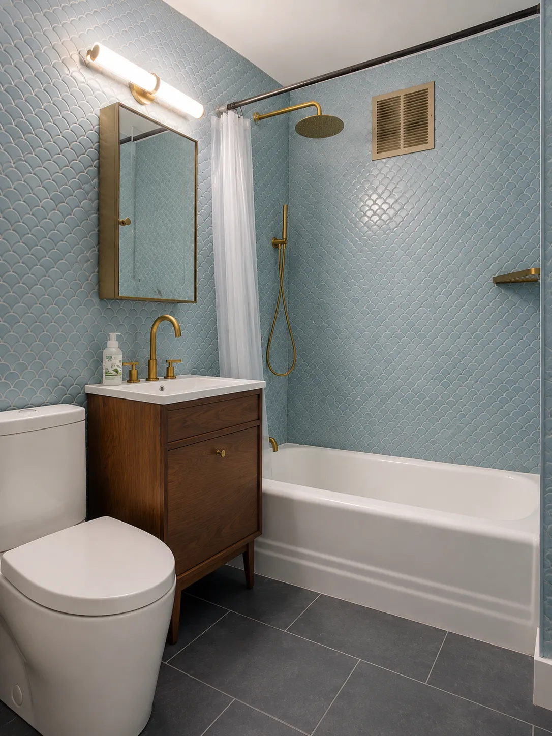 Studio bathroom with blue fish-scale tile, brass fixtures, and a walnut vanity in a Prospect Heights prewar apartment