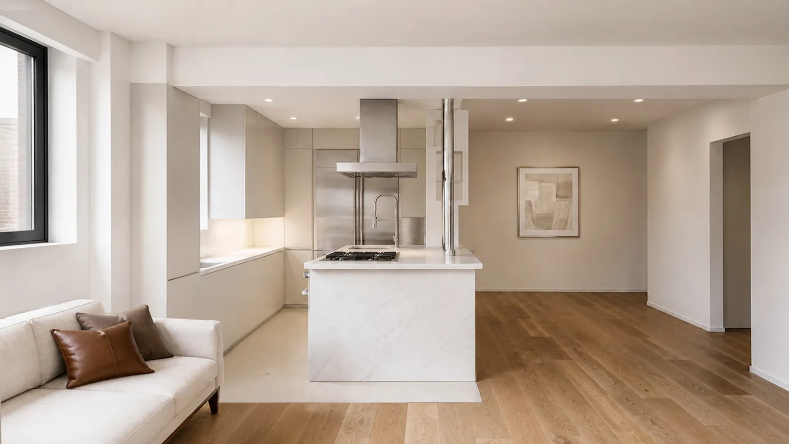 Open Upper East Side kitchen and living room with a marble waterfall island, stainless hood, cream sofa, and warm oak floors