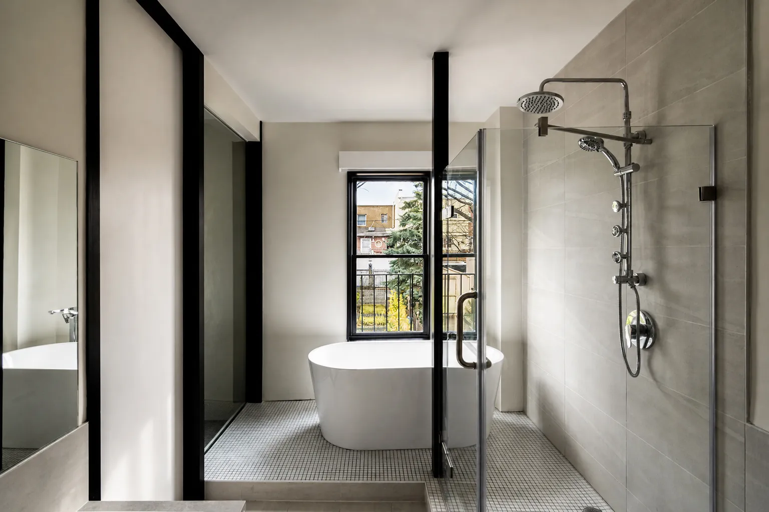 Manhattan master bathroom with a freestanding tub under a black-framed window and a glass walk-in shower with rain and body sprays