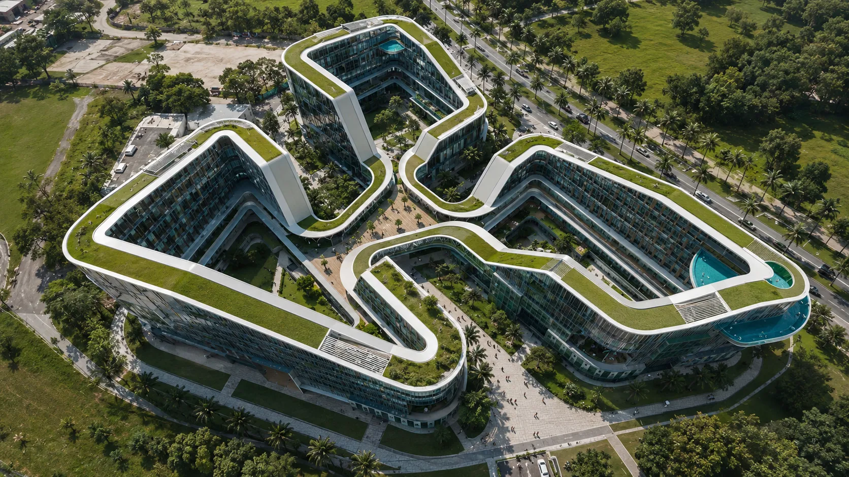 Overhead aerial of a curving green-roofed mixed-use resort complex set among palms and roadways