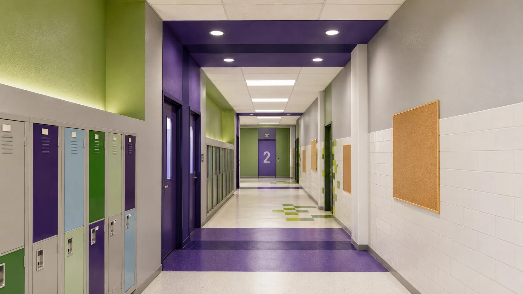 School hallway with color-coded lockers, green and purple accent walls, and banded floor tile in the Bronx, New York